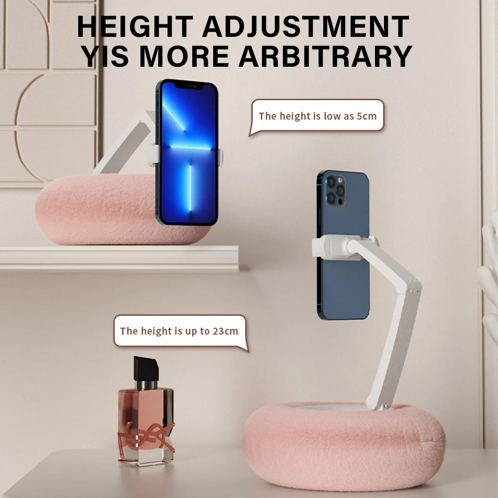 Phone holder with adjustable height shown next to a phone and perfume bottle on a shelf.