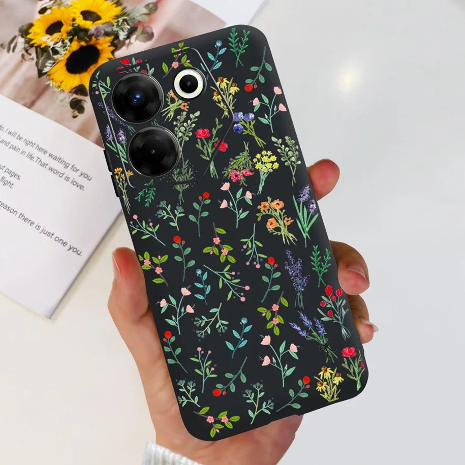 Phone case with floral pattern held by a hand, with flowers and a book in the background.